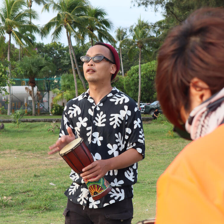 s.k (in floral black and white shirt) playing a mini djembe at the beach.